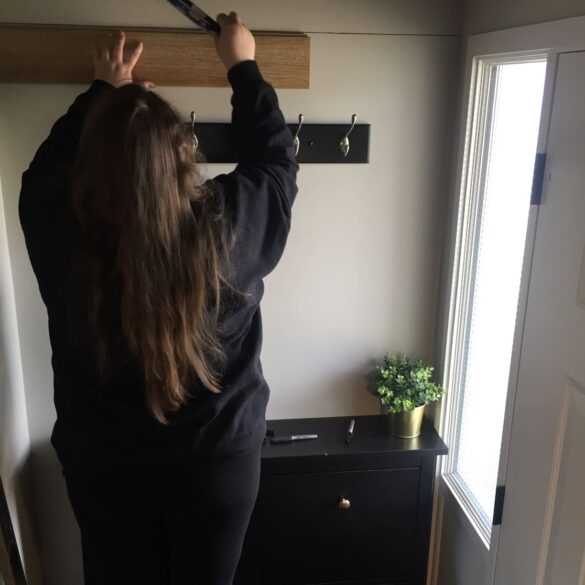 Holding a plank of flooring on wall, I am using it to measure the width between my shiplap lines.