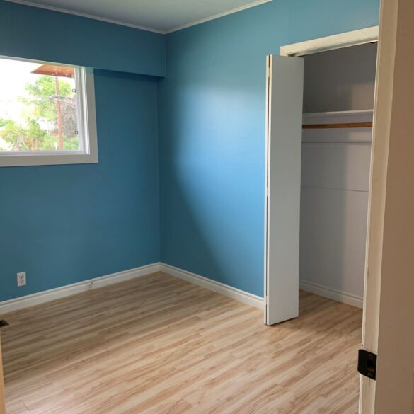 An empty bedroom, all the walls are  bright baby blue with white trim. 