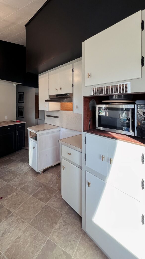 phase 3 of the kitchen has started. Part of the wall has been demolished. the stove range has been moved out of the hole. You can see the white cabinets from the 60s remaining, while the new black cabinets are in the background.