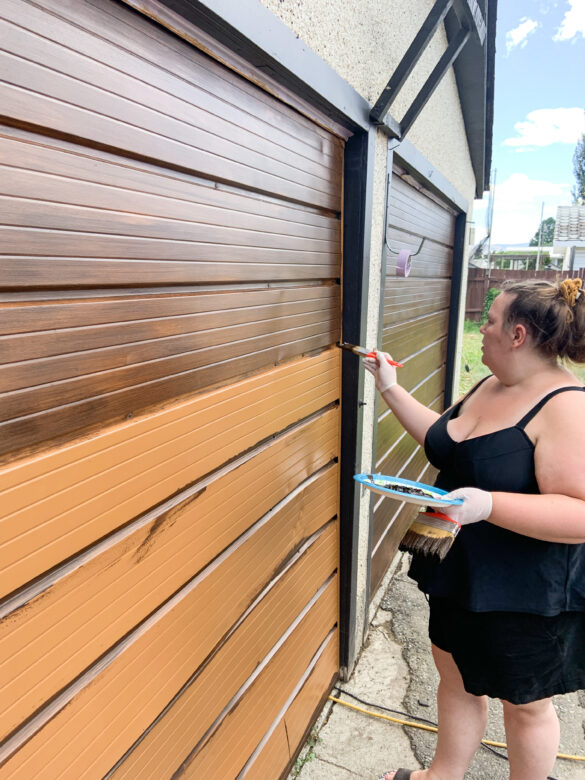 brown garage door is being painted with gel stain. part of door is light brown and the top is darker brown where the stain is applied.