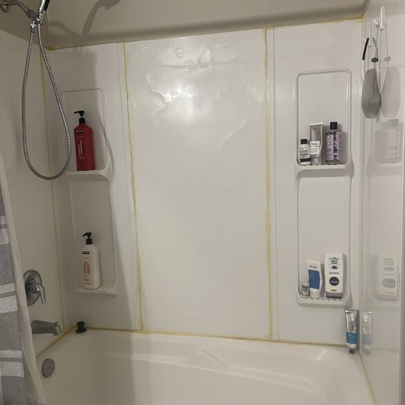 white bath shower surround where the caulk has yellowed