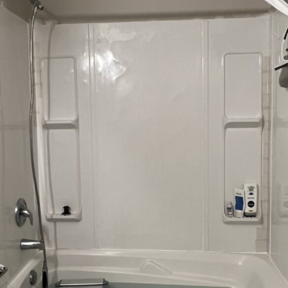 tub shower surround that has white caulk and tape on corners